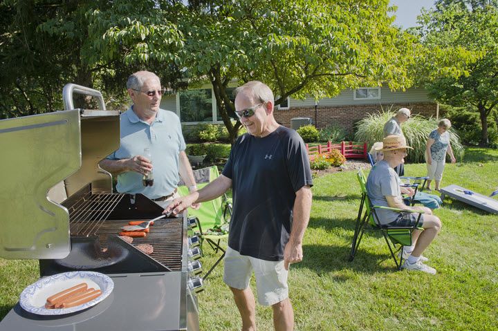 A group of people enjoying a barbecue in a sunny garden.