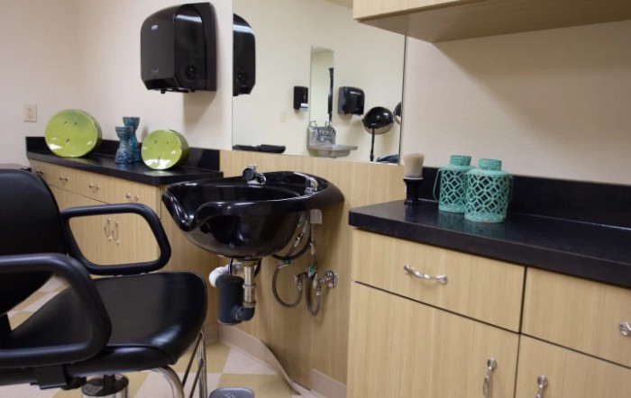 A hair salon interior featuring a washing station with a black sink and chair.