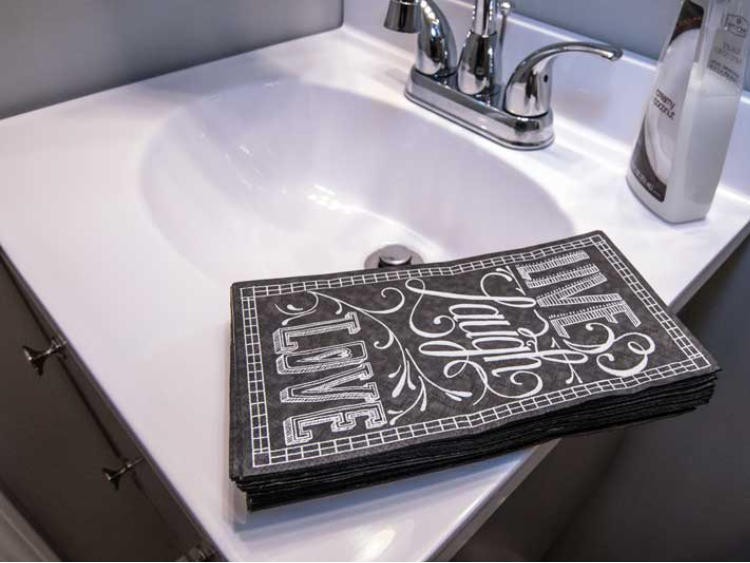 A bathroom sink with a decorative towel displaying the words 'Live Laugh Love'.