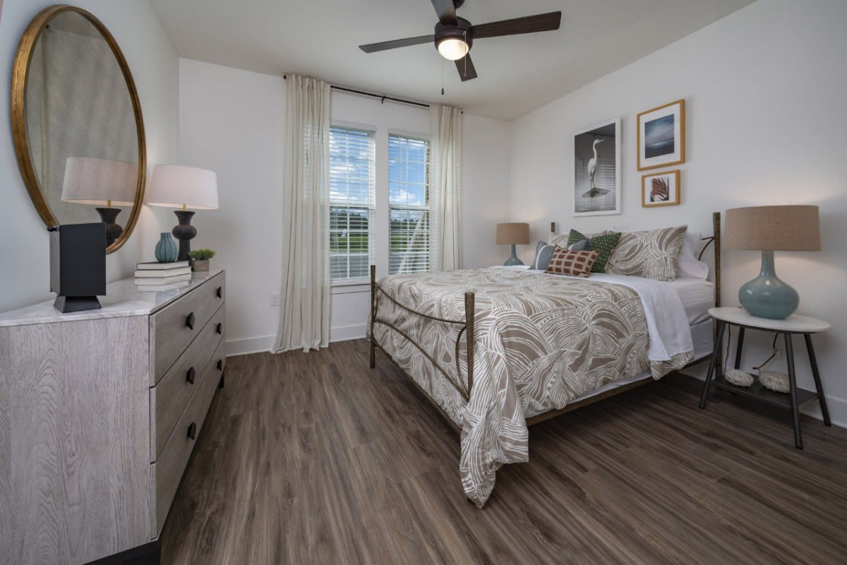 A modern bedroom with stylish decor, featuring a bed, artwork on the walls, and large windows letting in natural light.
