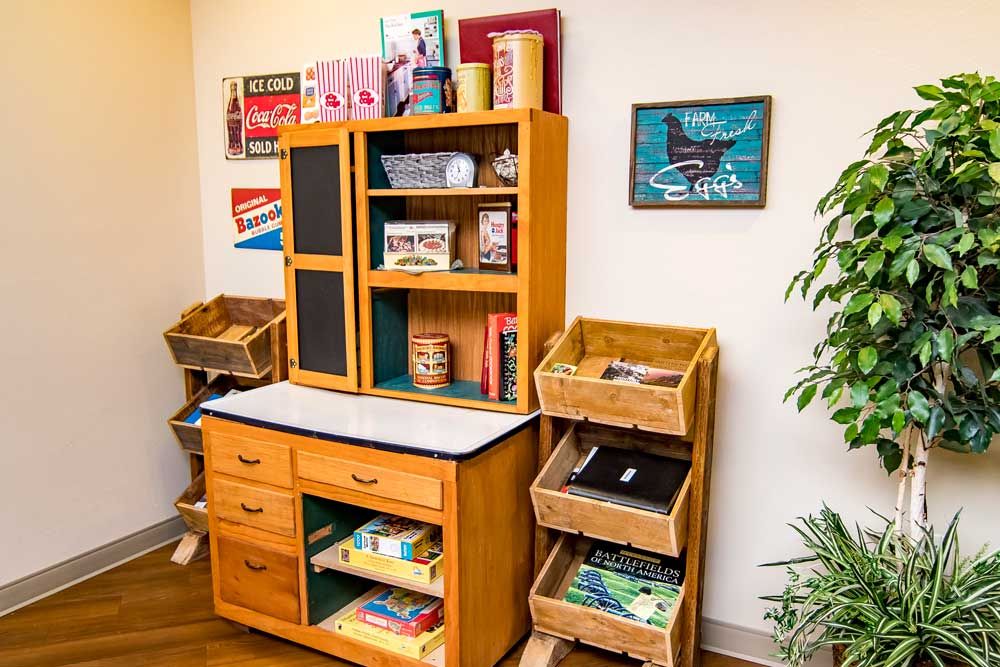 A children's play kitchen set with wooden shelves, baskets, and a miniature chalkboard.