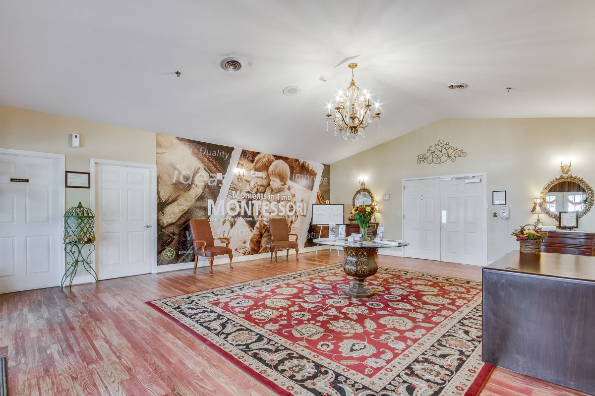 A tastefully decorated room with a chandelier, artwork on the wall, and a patterned carpet.