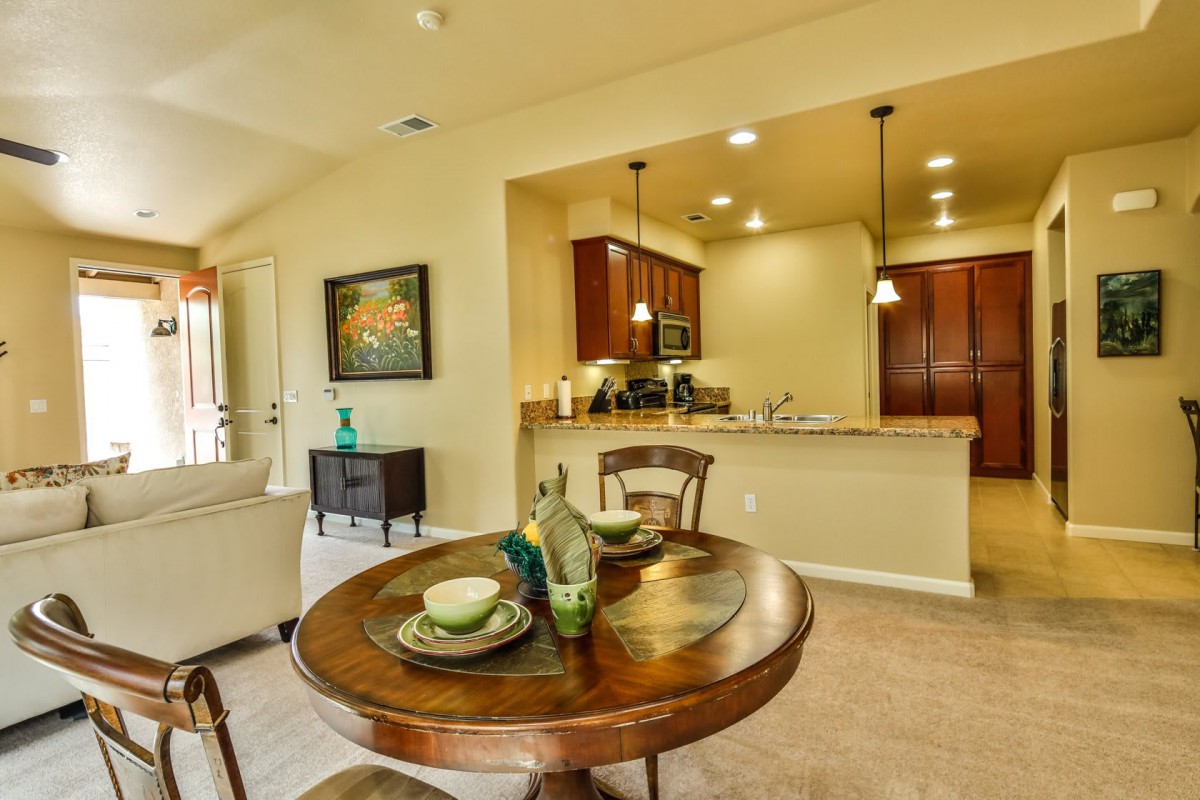 A modern open space dining area connected to a kitchen, featuring a round table set for two.