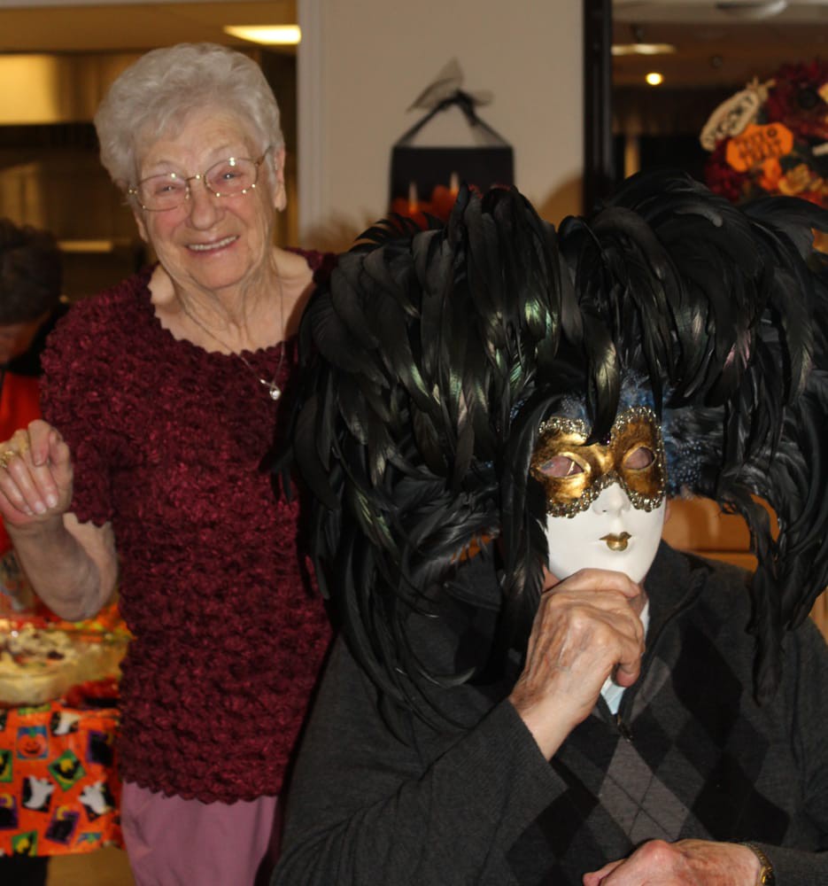 Two people at a party, one wearing an elaborate mask.