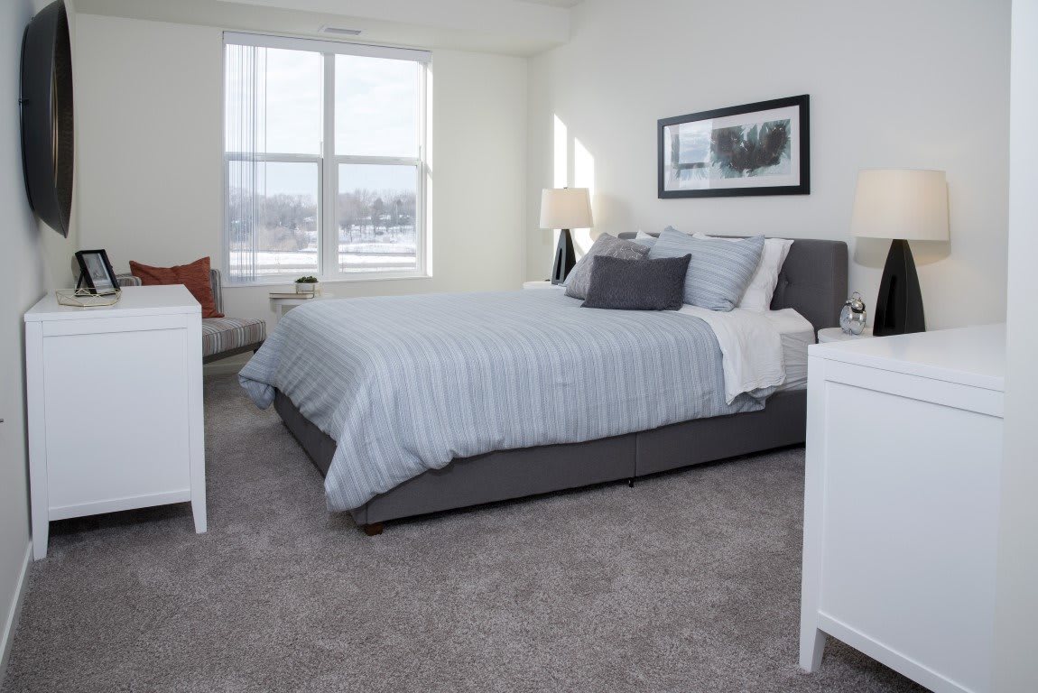 A modern and cozy bedroom with minimalistic decor, featuring a large bed and natural lighting from the window.