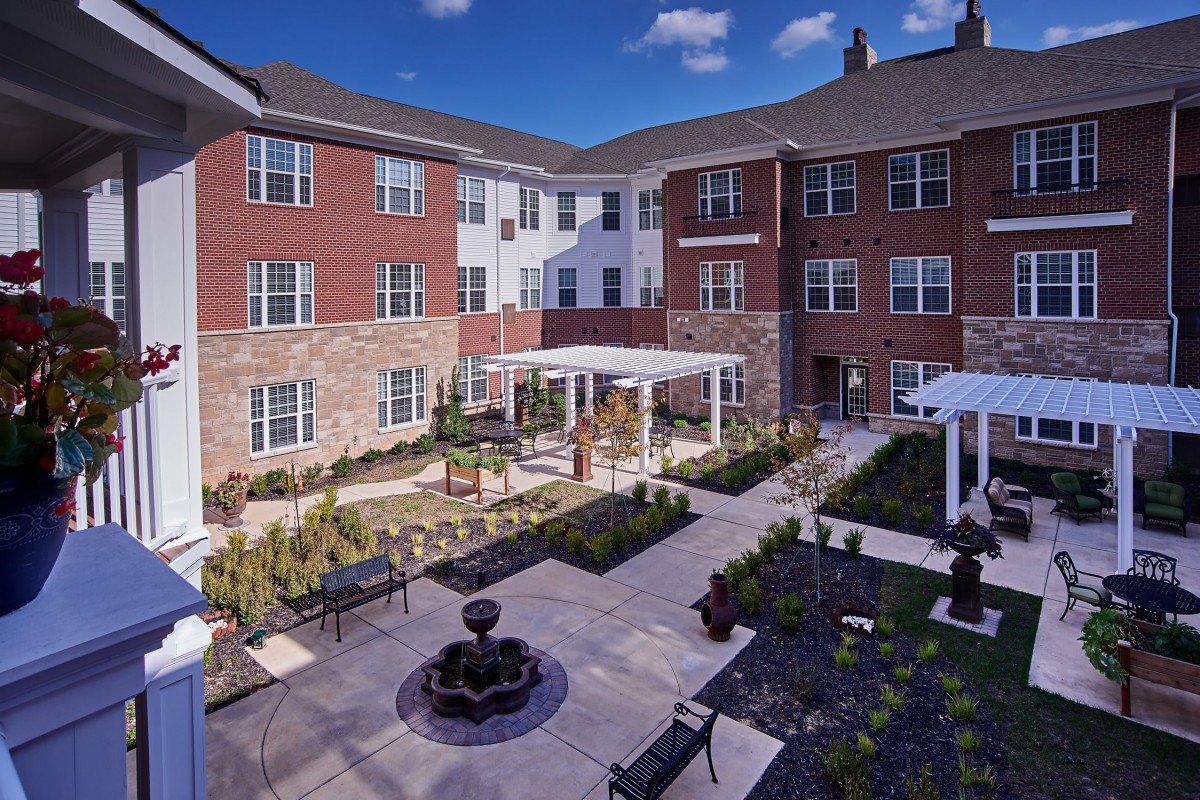 A well-maintained residential apartment complex with a central courtyard featuring a garden and outdoor seating areas.