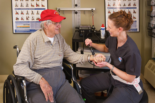 A healthcare professional assists an elderly patient during a medical check-up in a clinic.