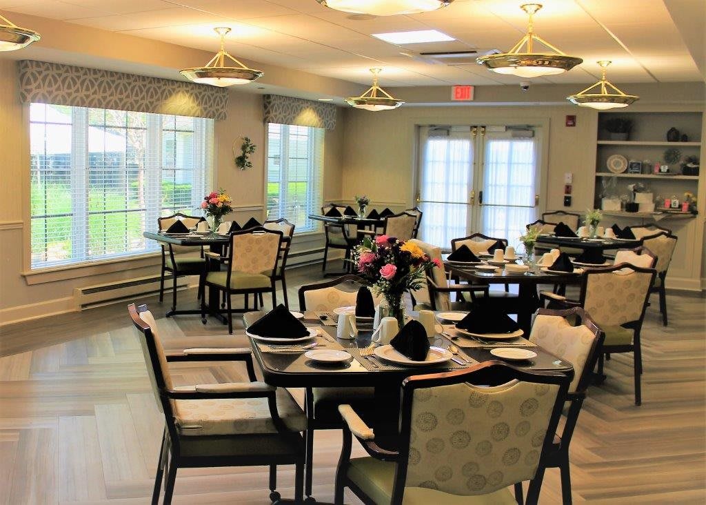 A neatly arranged dining room with tables set for a meal, featuring elegant decor and floral centerpieces.