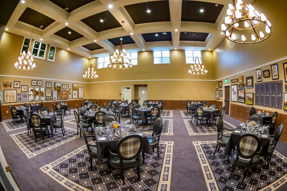 A spacious dining area with elegant chandeliers and neatly arranged tables and chairs.
