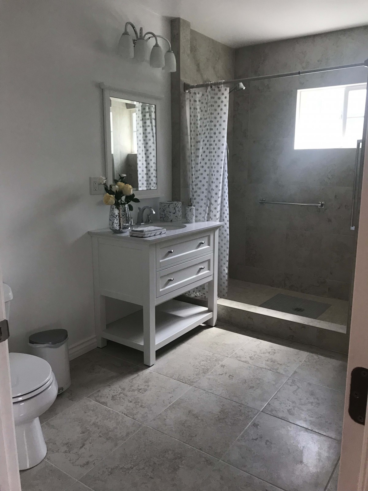 A modern bathroom with a vanity, mirror, and spacious shower area.