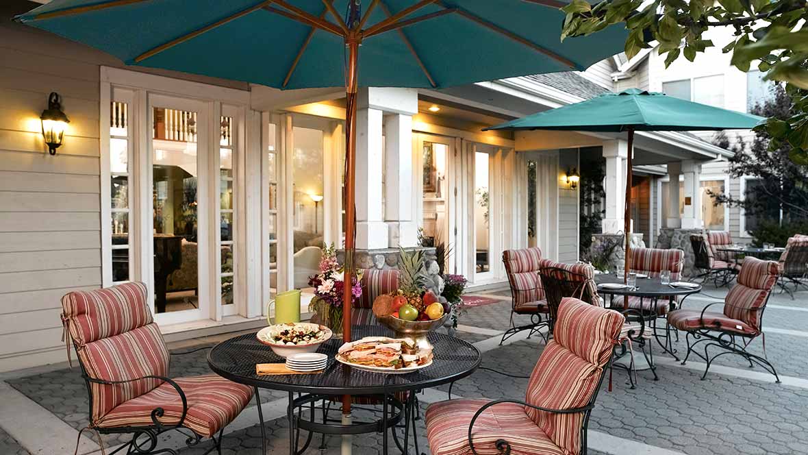 A cozy outdoor patio with tables and chairs set up for a meal under large umbrellas.