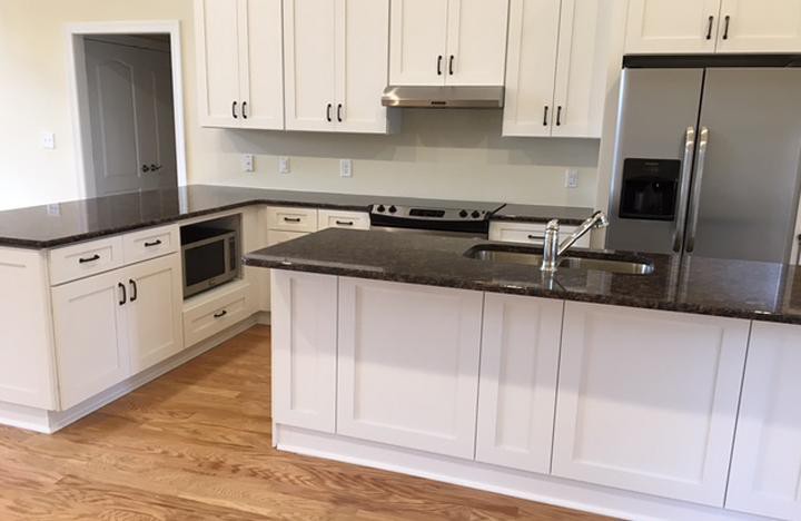 A modern kitchen featuring white cabinets, granite countertops, and stainless steel appliances with a central island.