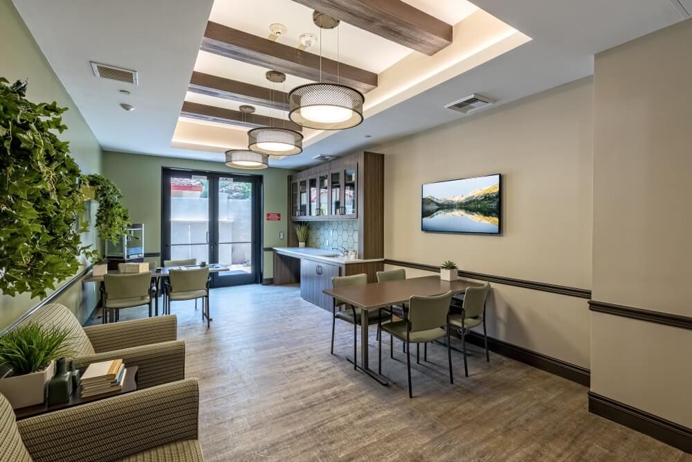 A modern lounge area featuring comfortable seating, a dining table, and wall art.