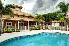 A luxurious tropical house with a swimming pool surrounded by palm trees.