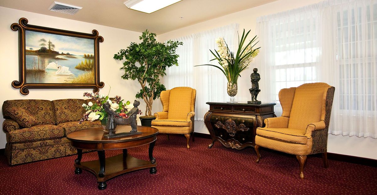 A classic-style living room with yellow chairs and decorative plants.