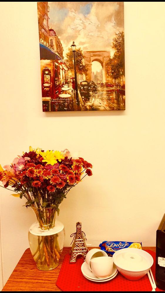 A vase of vibrant flowers sits beneath a colorful cityscape painting.