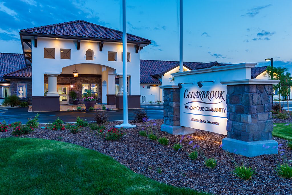 A well-lit hotel entrance at dusk with manicured landscaping.