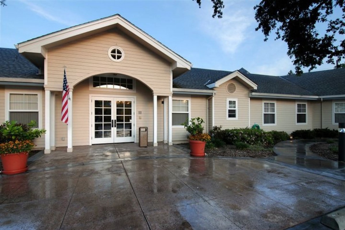 A residential house with an arched entrance, a potted plant, and an American flag by the driveway.