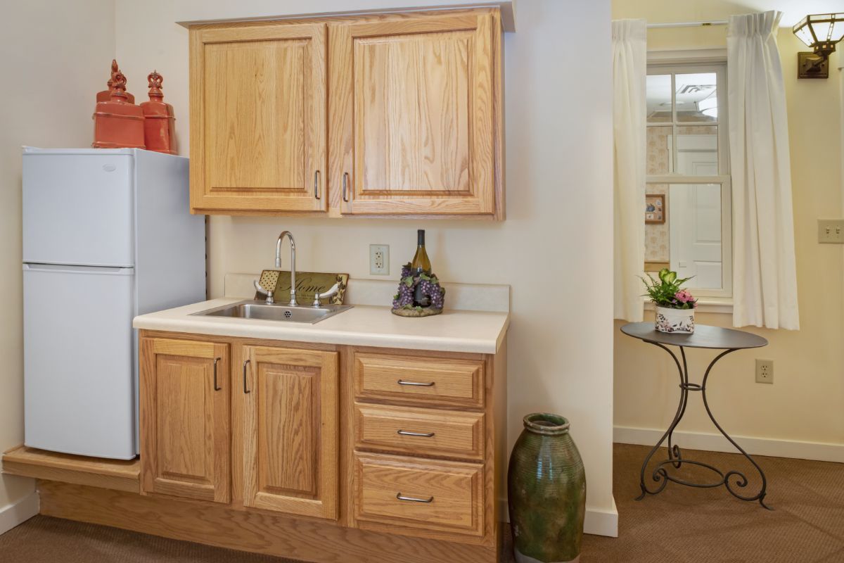 A cozy kitchen area featuring wooden cabinets and a small countertop with a sink, complemented by decorative items.