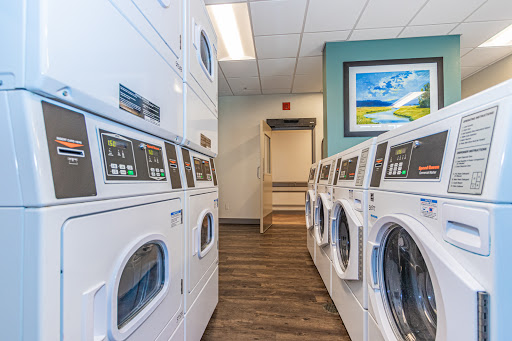 A modern laundry room equipped with efficient washing machines and dryers, featuring a comfortable and inviting atmosphere.