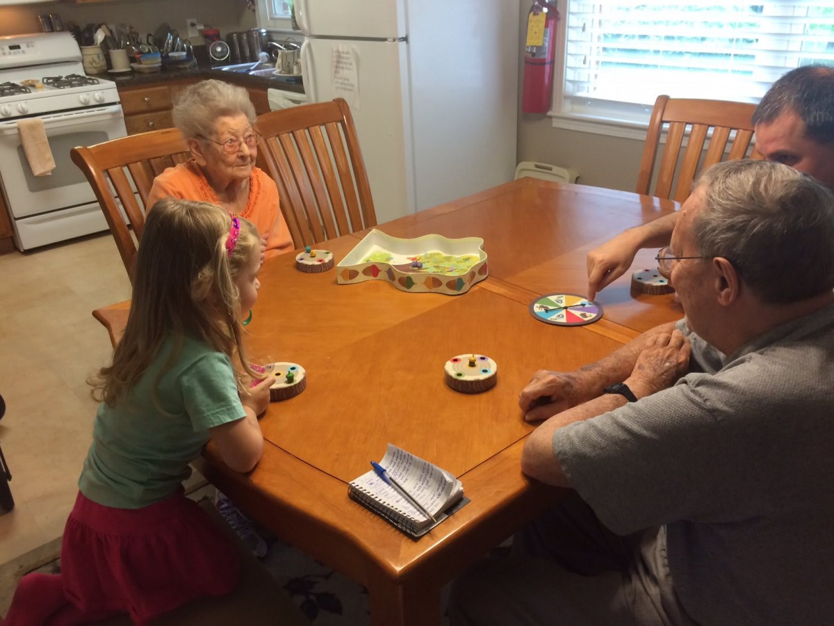 A family playing a board game together at a dining table.
