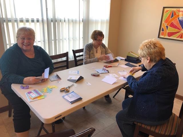 Three people sitting at a table working with papers in an indoor setting.
