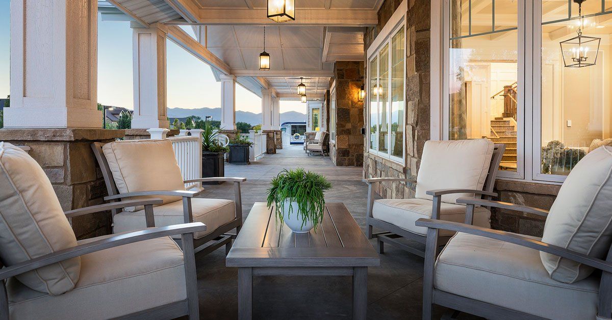 A cozy outdoor patio with comfortable seating and a table under soft lantern lighting.