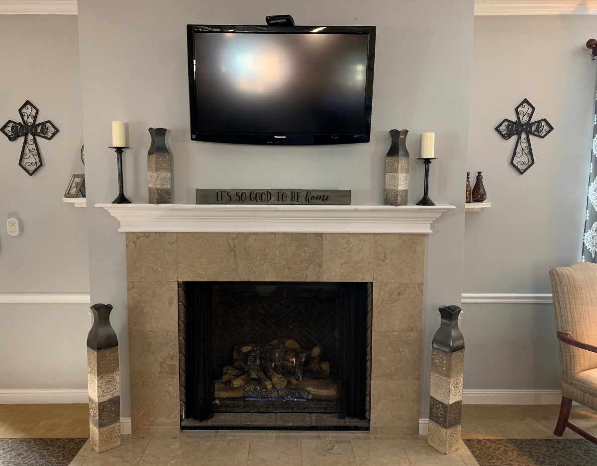 A modern living room with a fireplace and mounted TV, adorned with decorative vases, candles, and wall art.