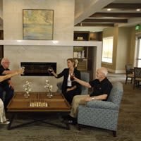 A group of seniors enjoying a casual gathering in a cozy living room with a fireplace.