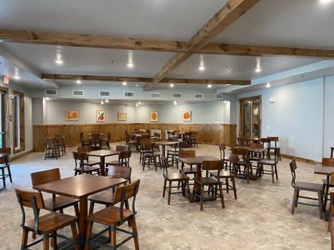 An empty restaurant dining area with wooden tables and chairs, well-lit and neatly arranged.