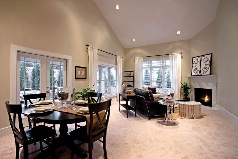 A spacious living room with a connected dining area, featuring large windows and elegant furniture.