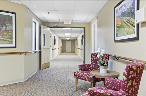 A serene hospital hallway featuring a comfortable waiting area with floral-patterned chairs.