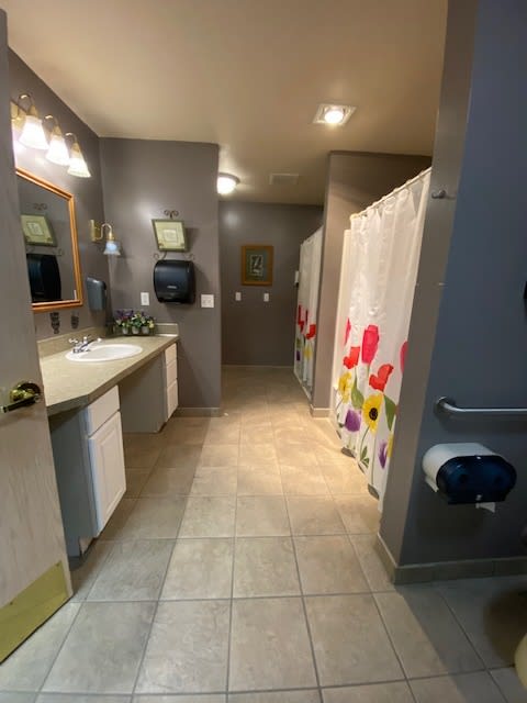 A clean public bathroom with multiple sinks, mirrors, and shower stalls with colorful curtains.