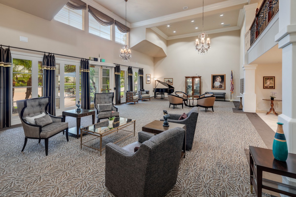 A spacious living room with elegant decor, featuring a piano and large windows.