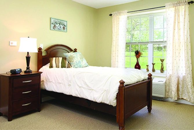 A cozy bedroom with a wooden bed and a large window.