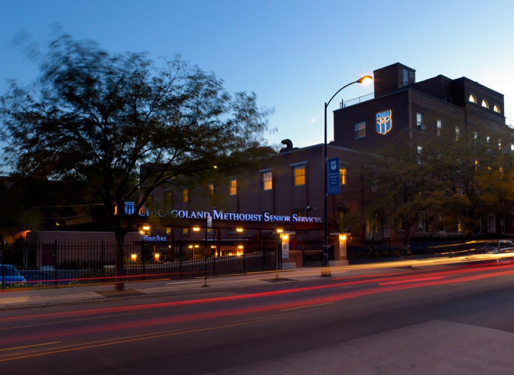 A restaurant lit up during the evening on a busy city street.