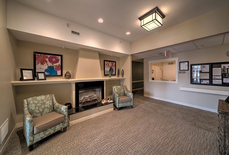 A cozy lobby with a fireplace, seating area, and artwork on the walls.