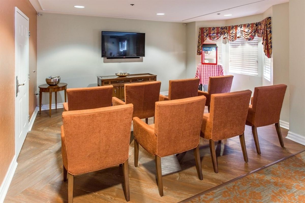 A cozy room setup with orange chairs facing a television for presentations or viewing.