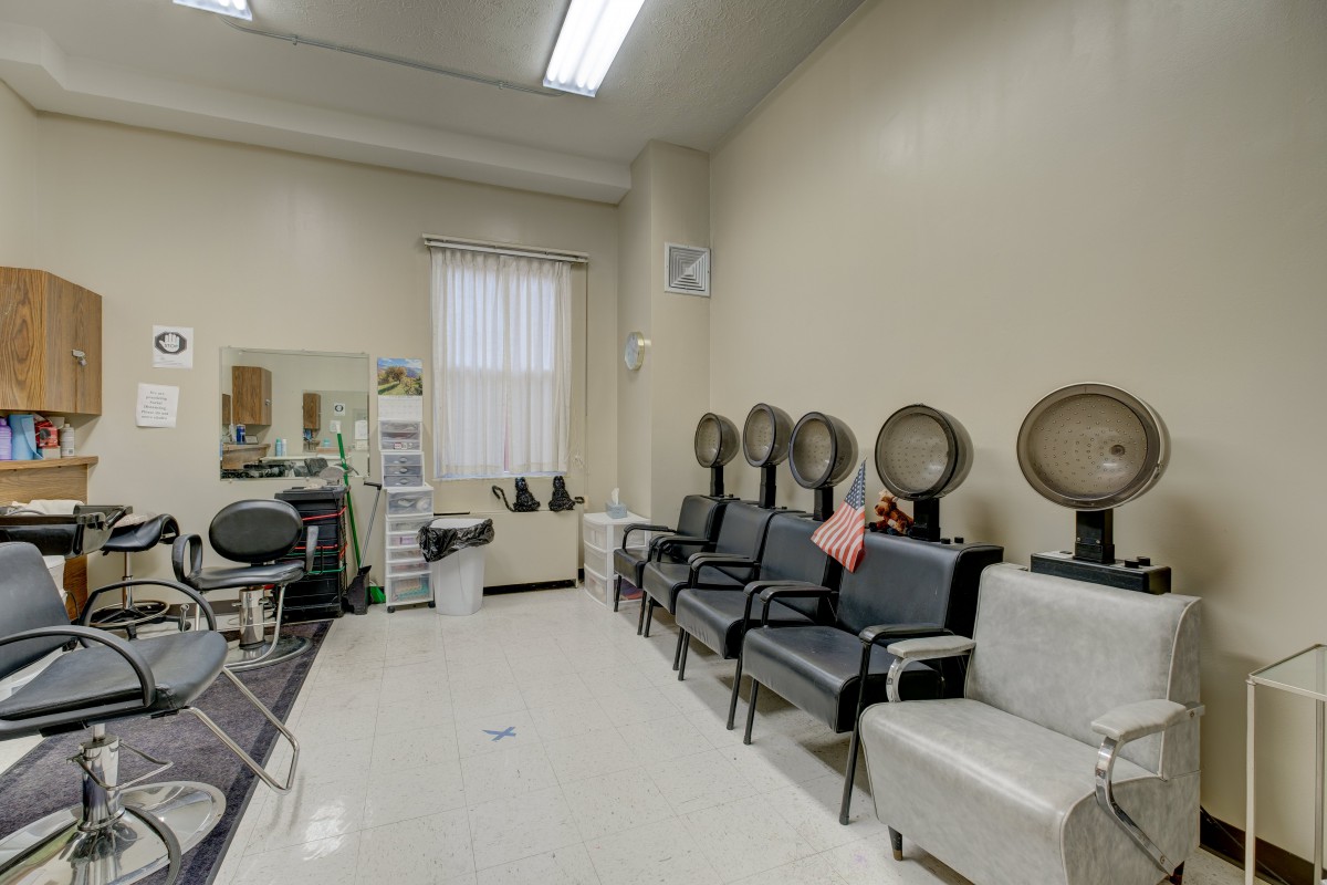 An empty beauty salon with multiple hair dryers and chairs.