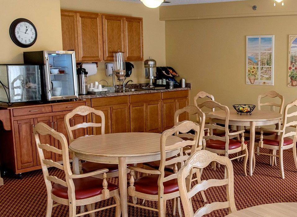 A cozy dining area featuring tables and chairs, with a coffee station in the background.