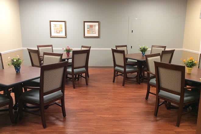 A neatly arranged dining room with several tables and chairs on a wooden floor.