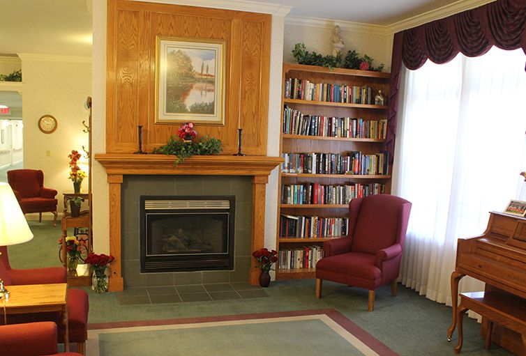 A cozy living room featuring a fireplace, bookshelves filled with books, and a comfortable armchair by the window.