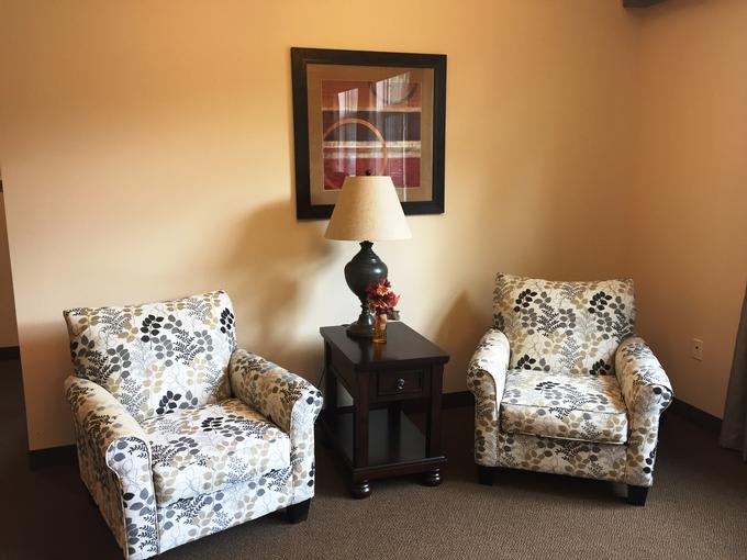 A cozy seating area with patterned armchairs and a side table with a lamp.