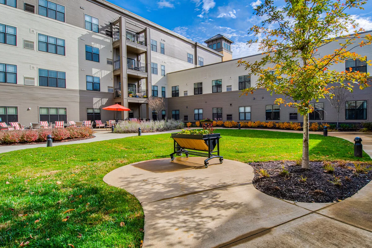 A courtyard view of a residential apartment building with a bench and landscaped garden.