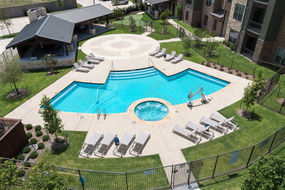 Aerial view of a residential swimming pool area with sun loungers and a hot tub.