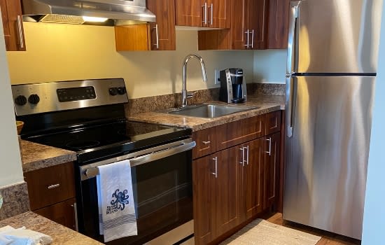 A modern kitchen with stainless steel appliances and wooden cabinetry.