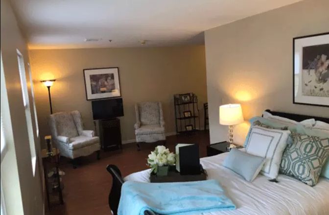 A cozy bedroom with a neatly made bed, soft lighting, and comfortable seating.