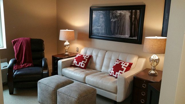 A cozy living room with a white sofa, red and white patterned pillows, warm lighting, and wall art.