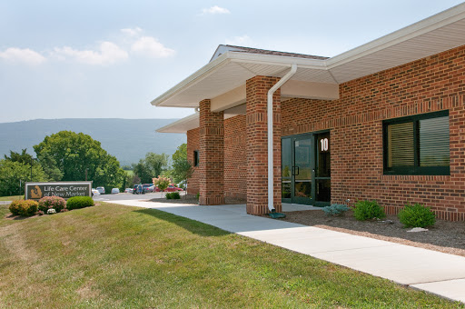 A modern brick building surrounded by green grass and a clear sky.