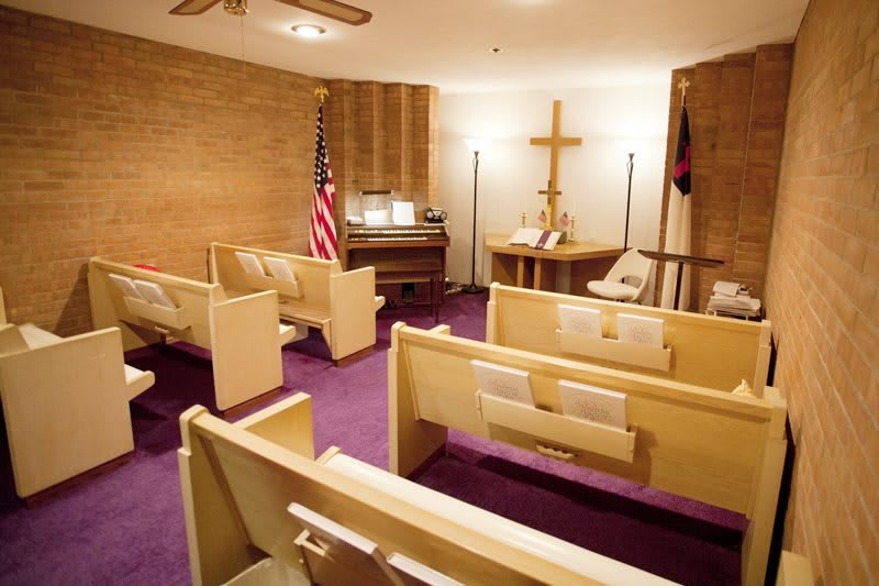 A small chapel with pews, a cross, an American flag, and an organ.